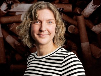 Madelene Pollnow i förgrunden. Cigaretter i bakgrunden för att illustrera om ensamhet är lika farligt som rökning.