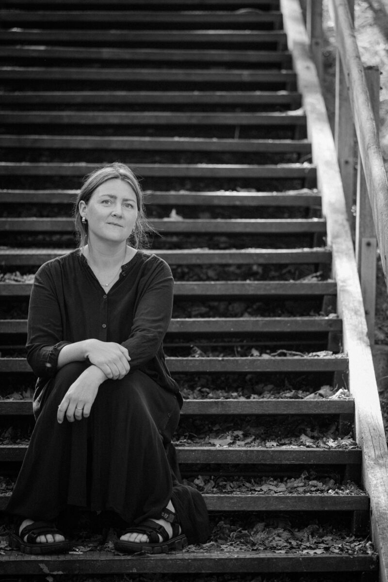 Maja Larsson författare av Föräldrars födelse sitter i en trappa.