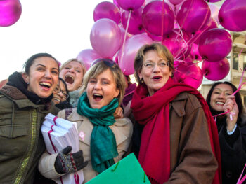 Ett glatt gäng människor från Feministiskt initiativ med rosa ballonger. I fronten Devrim Mavi, Sofia Karlsson och Gudrun Schyman med dokument.